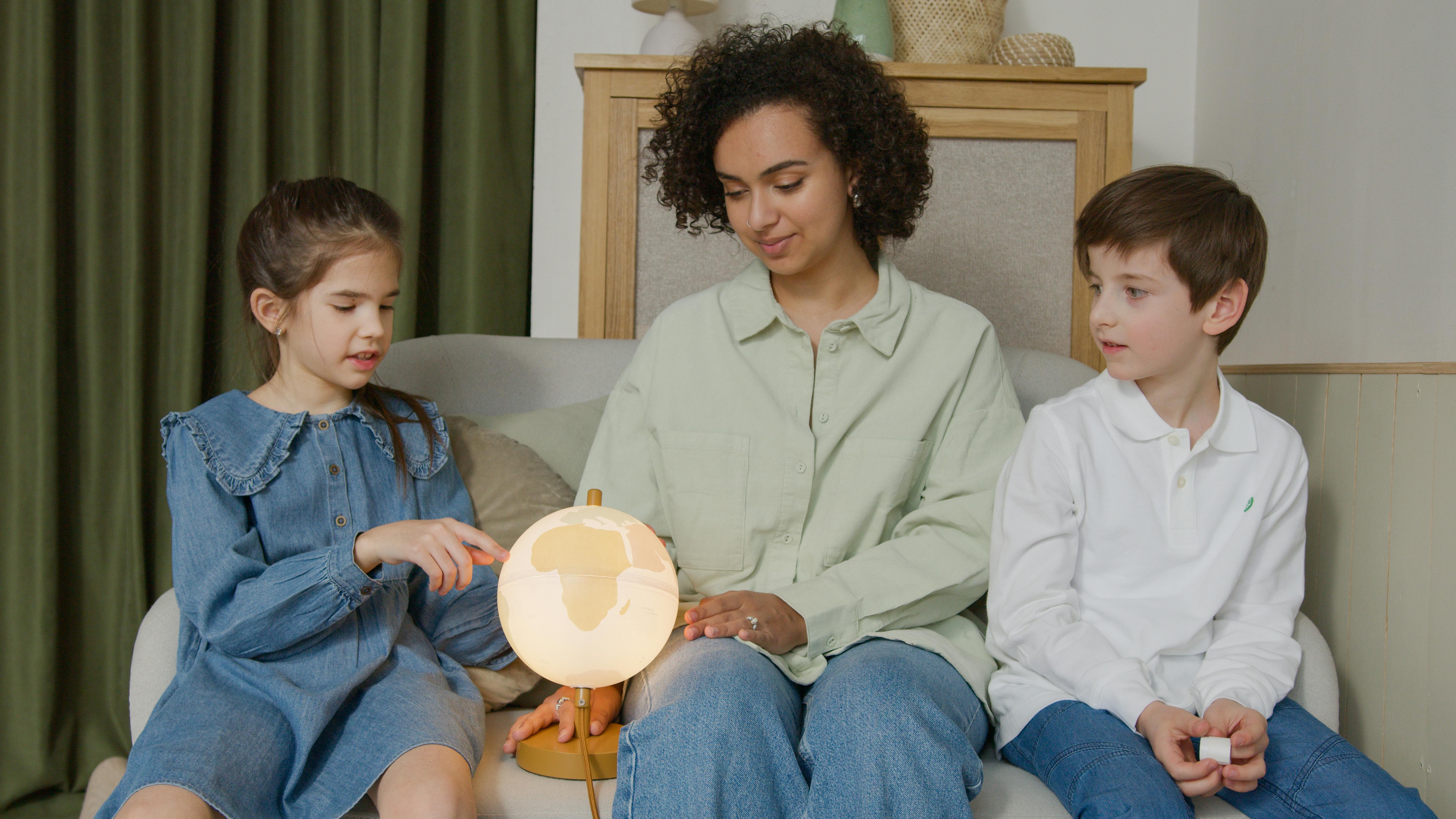 a woman looking at a globe with children