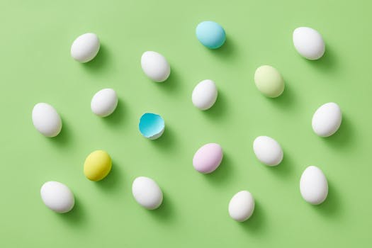 Brightly colored Easter eggs with one broken egg shell on a green background.
