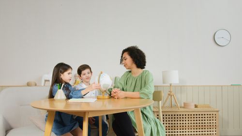 Free Children and teacher using a globe for a geography lesson in a classroom setting. Stock Photo