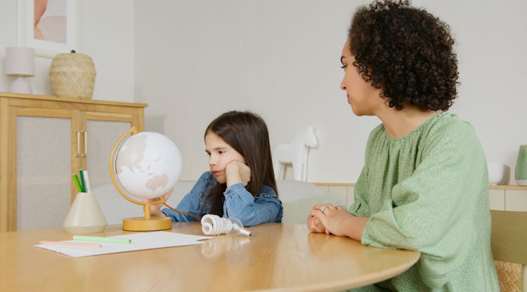 A Kid Looking At The Globe On The Table