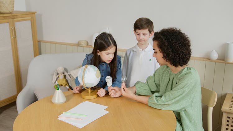 Mother Sitting And Showing Light Bulbs To Children