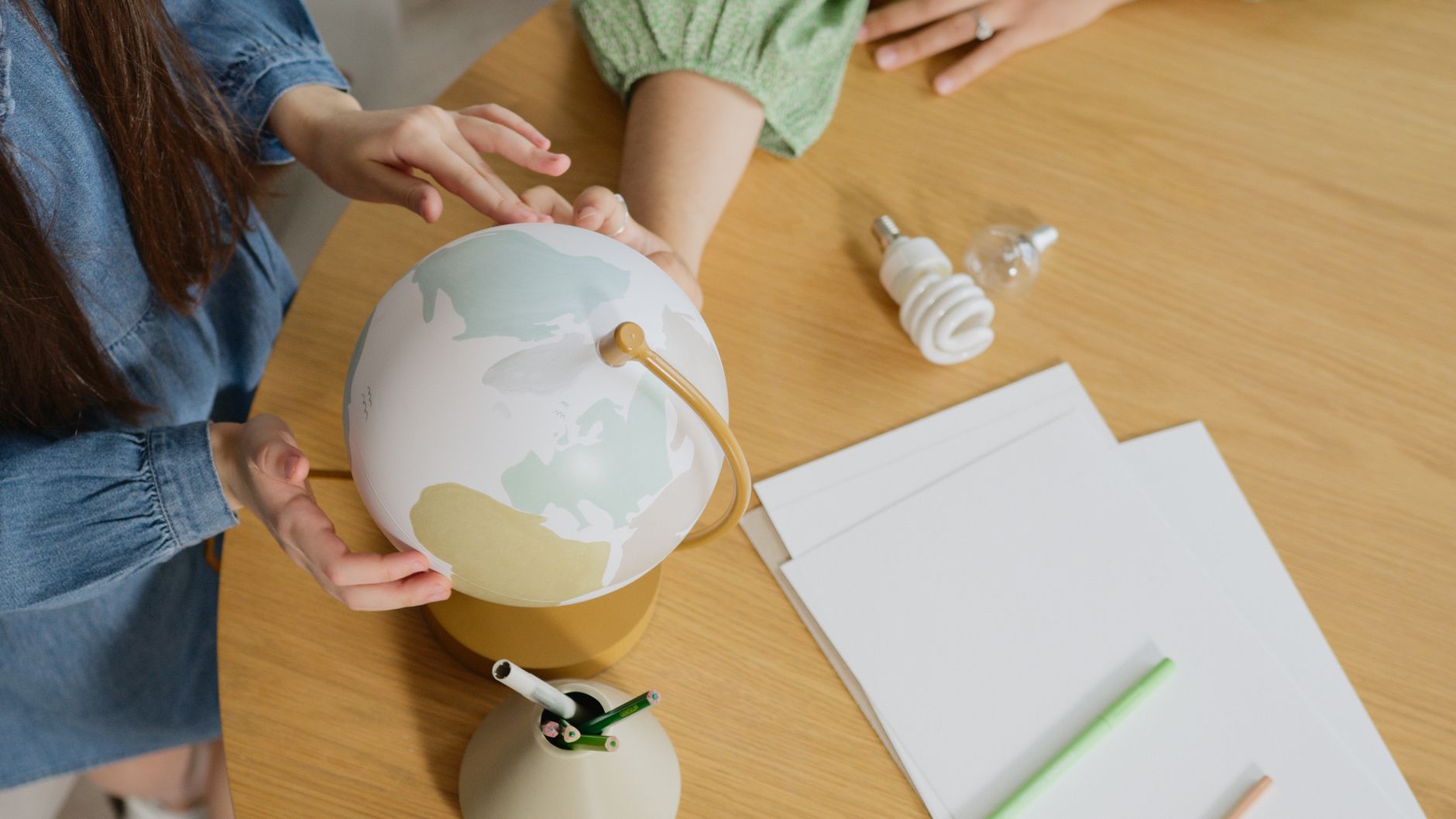 A close-up of hands exploring a tabletop globe, symbolizing global education and curiosity.