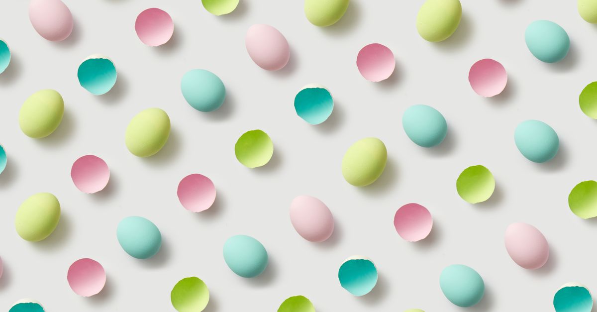 Flat lay of pastel-colored eggshells in a playful pattern on a white background. Perfect for Easter themes.