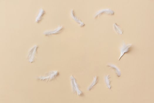 Capture of scattered white feathers on a soft yellow backdrop, ideal for design.