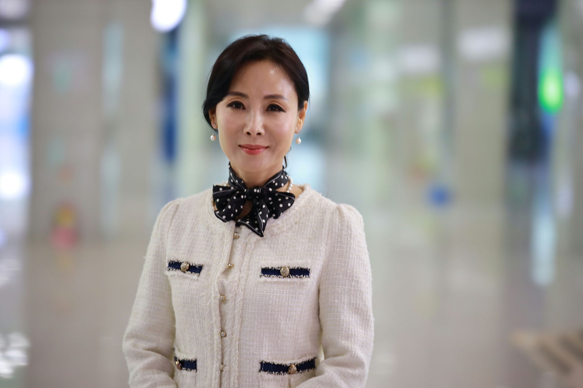 Portrait of an elegant woman with a polka dot scarf, smiling, captured in an indoor setting.