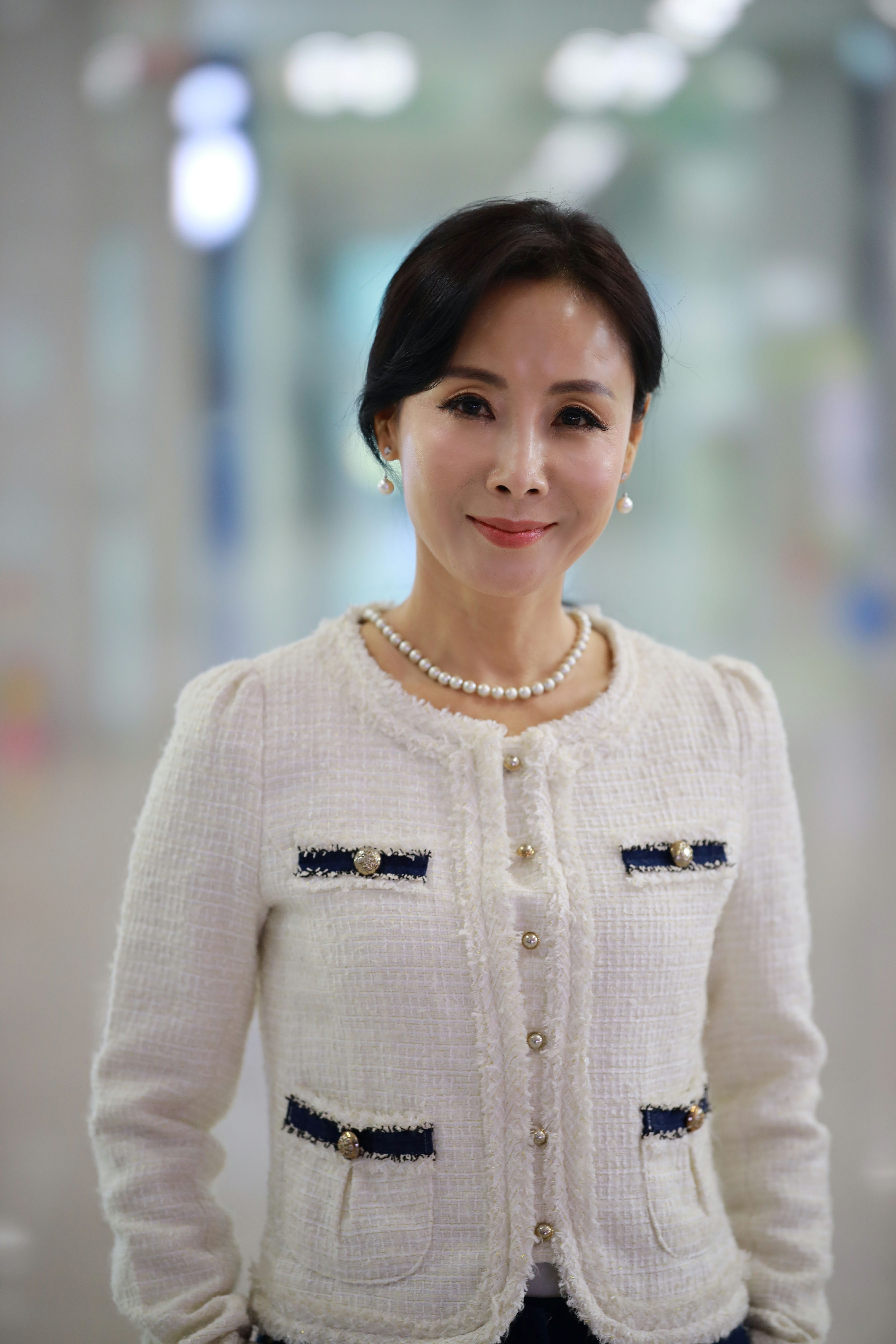 Chic portrait of a woman wearing an elegant white jacket, exuding grace and poise.