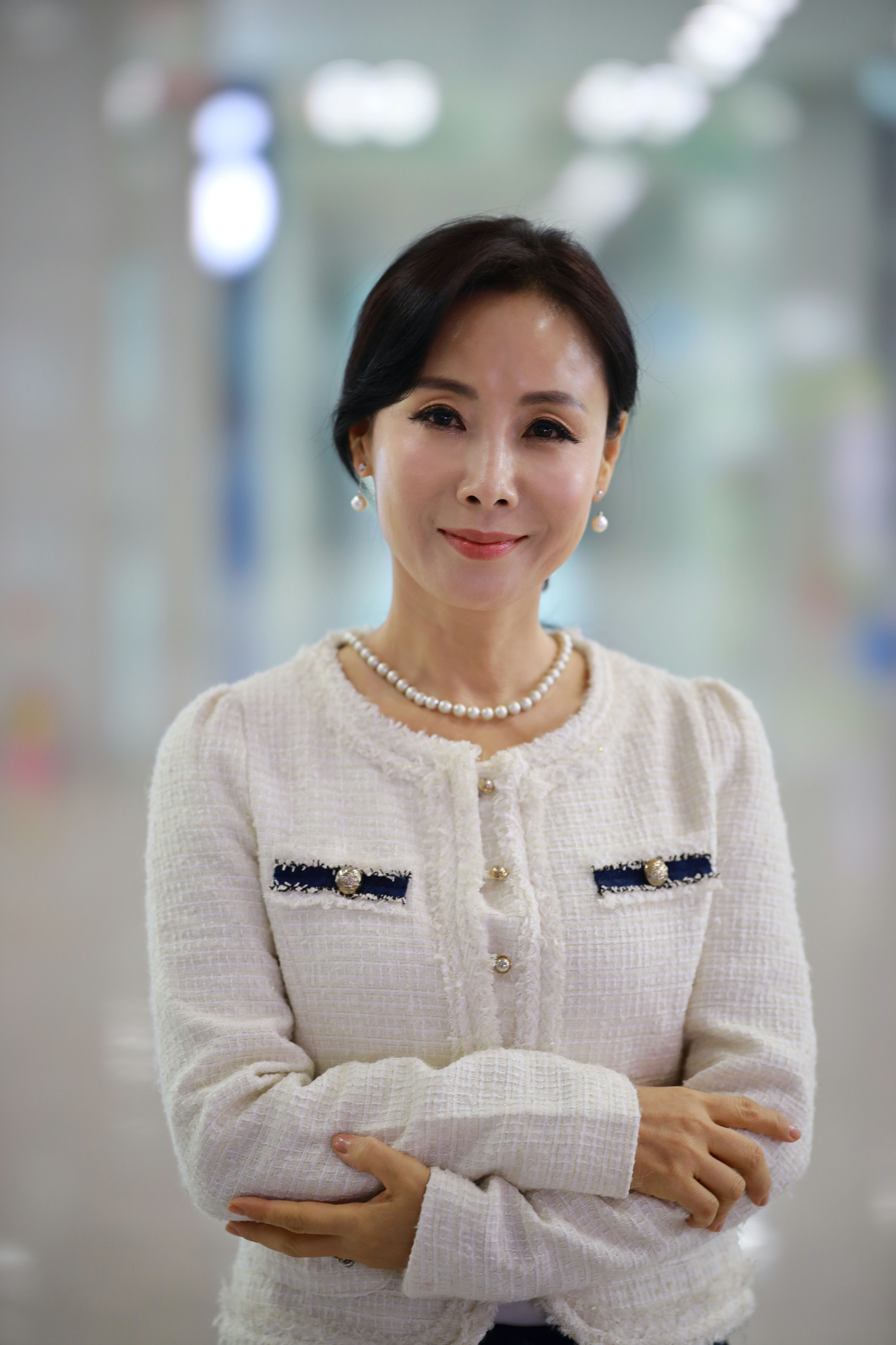 Sophisticated woman in elegant attire with a confident smile in a modern indoor space.