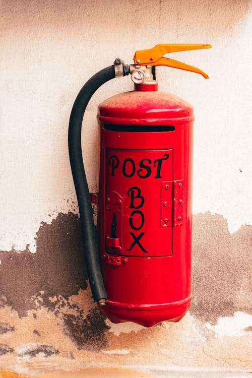 A Red Post Box Made of a Fire Extinguisher on Shabby a Wall