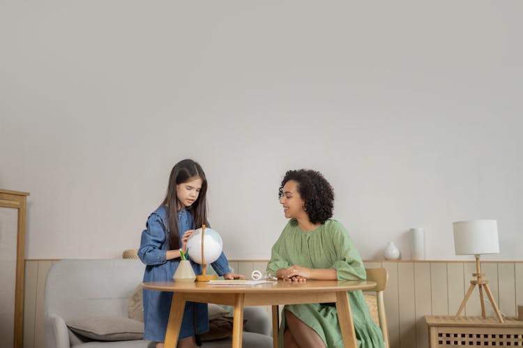 A Student And Teacher Looking At A Globe