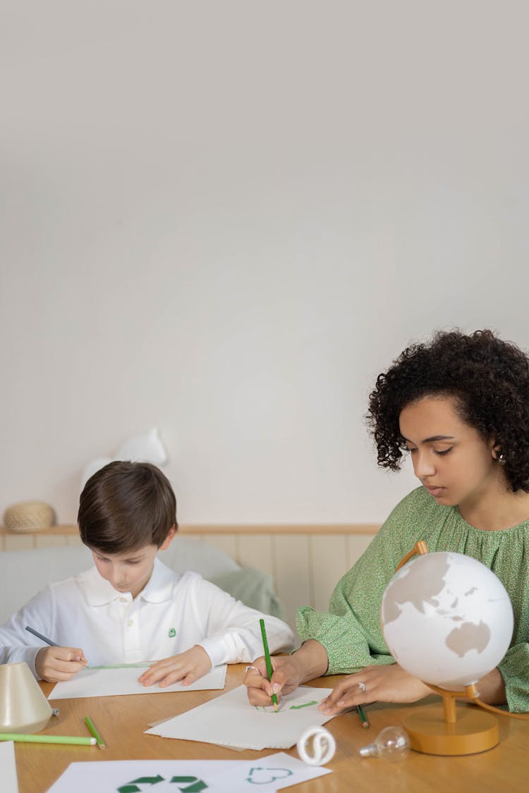 A Teacher And Her Student Drawing On Papers