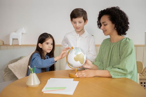 Free Children learning geography with a teacher and a globe, fostering curiosity. Stock Photo