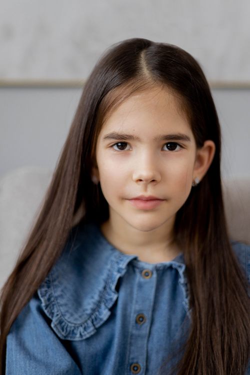 Free Close-up portrait of a young girl in a blue denim dress with long hair. Perfect for lifestyle themes. Stock Photo