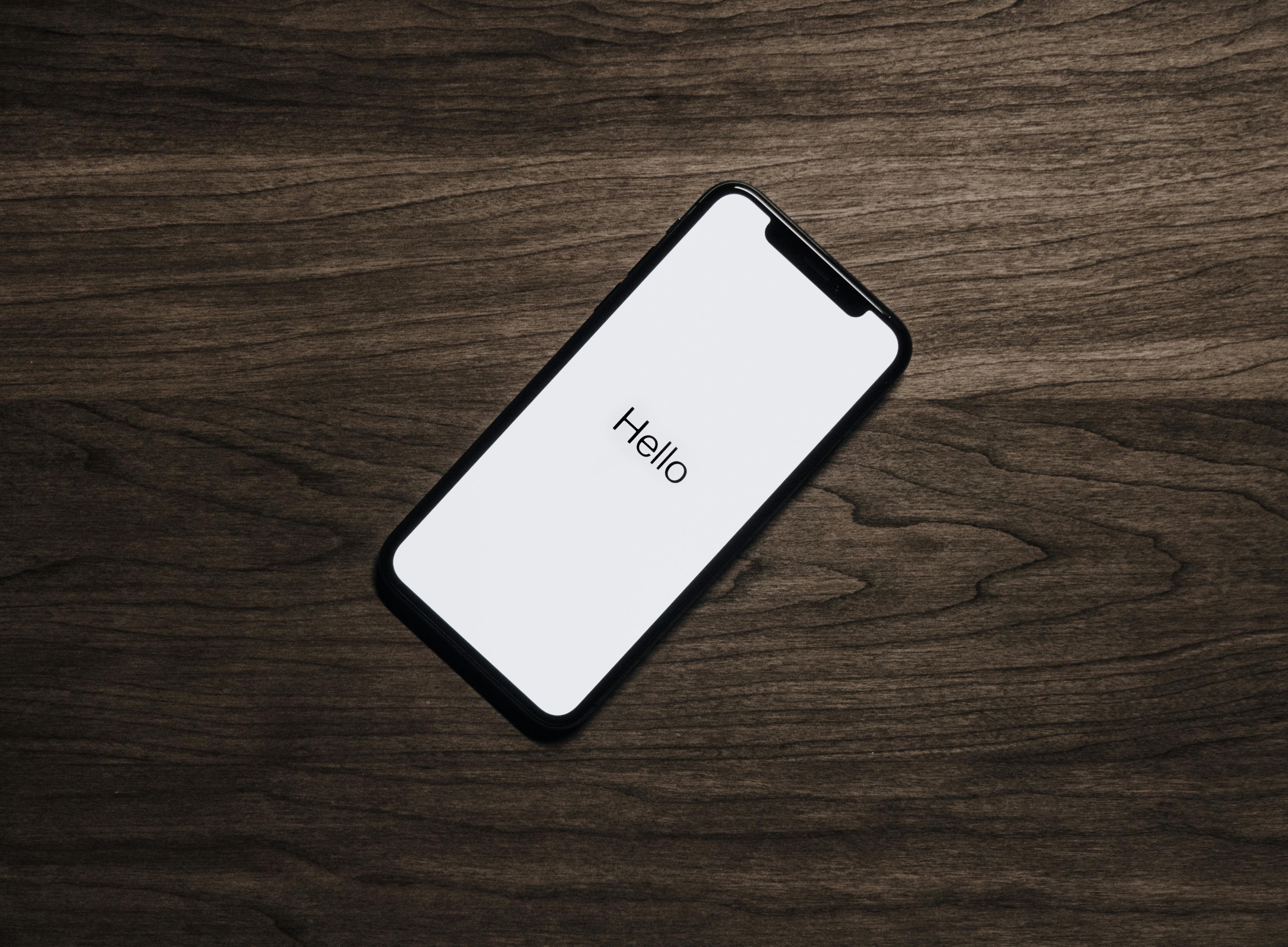 A mobile phone on the desk with "Hello" displayed