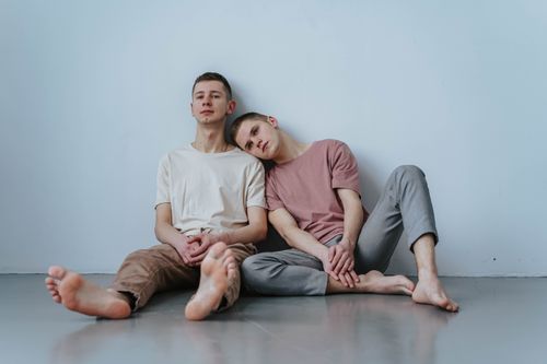 Free Two young men sitting together inside, sharing a tender and loving moment. Stock Photo