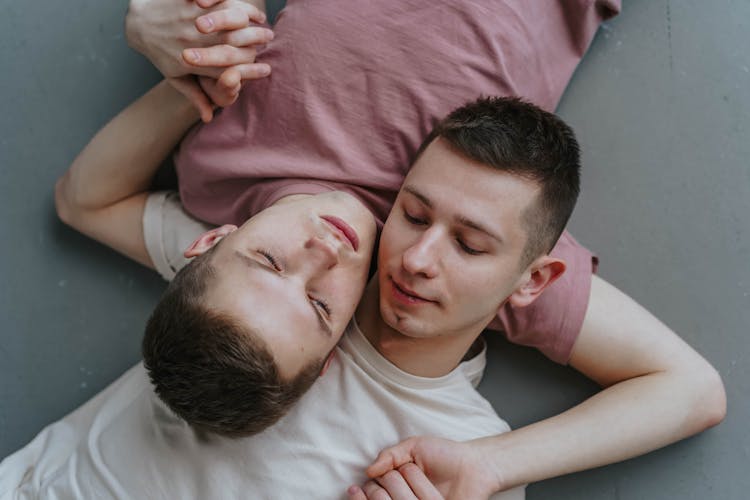 A Young Couple Lying Close Together Holding Hands