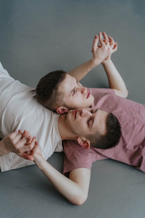 Free Photo of a Couple Holding Hands while Lying on the Floor Stock Photo