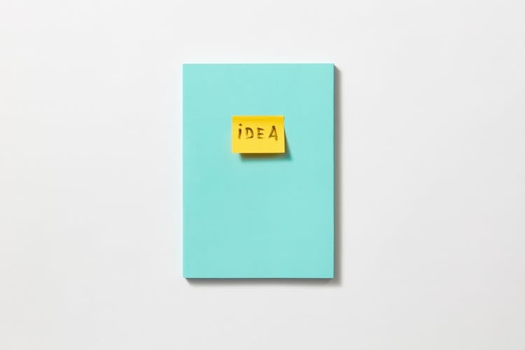 A Word Idea Written On A Yellow Post It Stuck On A Blue Board