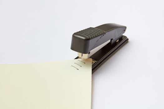 A close-up image of a black stapler fastening sheets of paper, ideal for office themes.