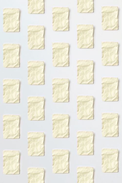 Free Overhead shot of crumpled paper sheets arranged in a grid pattern on a light surface. Stock Photo