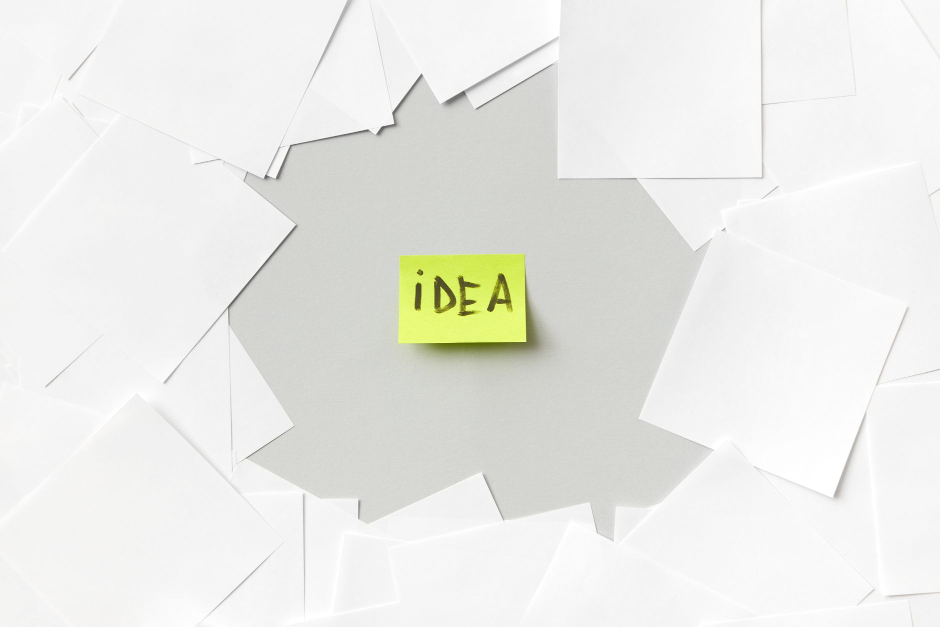 Yellow sticky note labeled Idea surrounded by white papers, symbolizing creativity.