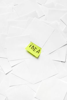 A stack of white papers with a bright yellow sticky note labeled 'idea' showcasing creativity.