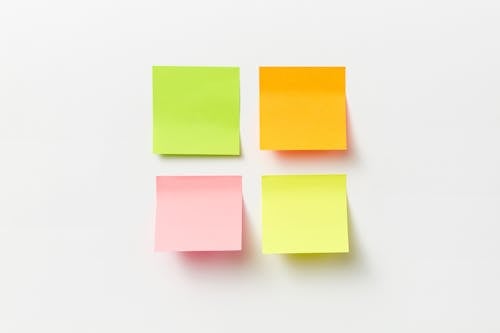 Free A Few Pieces of Post Its in Assorted Colors Stuck on a White Wall Stock Photo