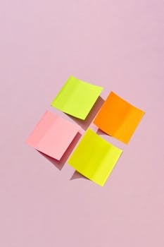 Vibrant sticky notes arranged on a pastel pink background, ideal for office and organization themes.