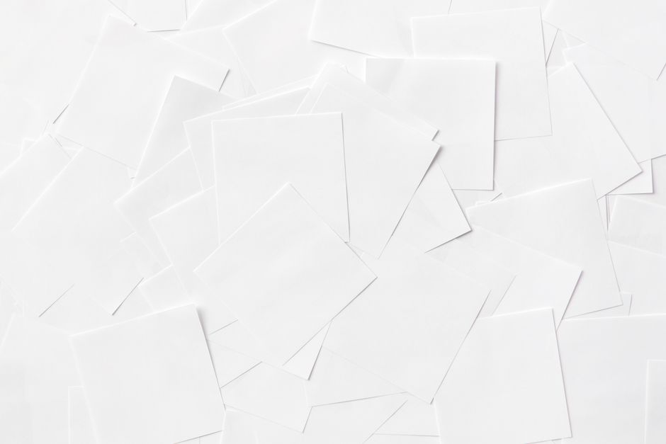 Overhead view of scattered white paper sheets creating an abstract pattern.