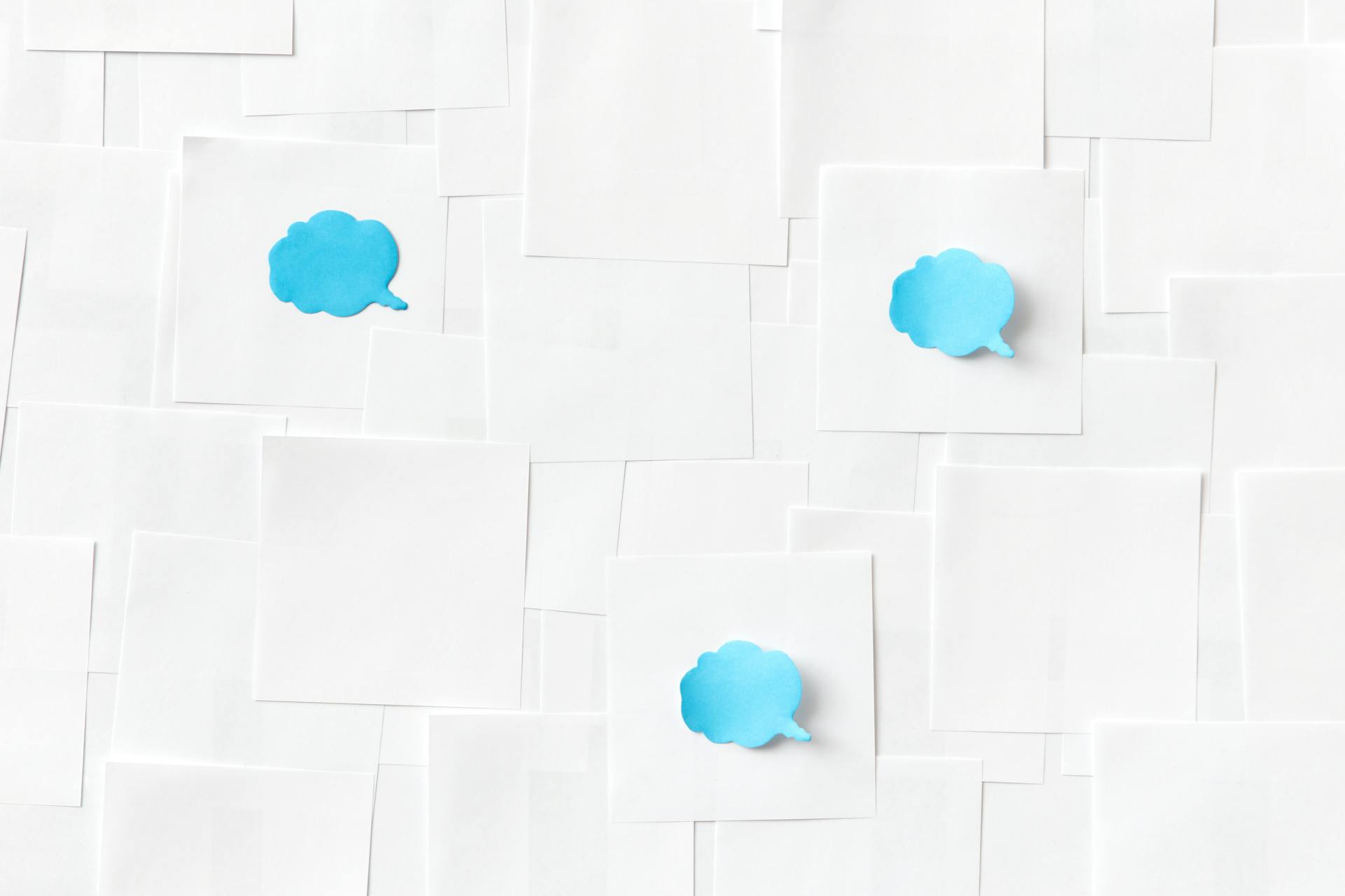 Creative image of blue speech bubbles on a white paper background for conceptual uses.