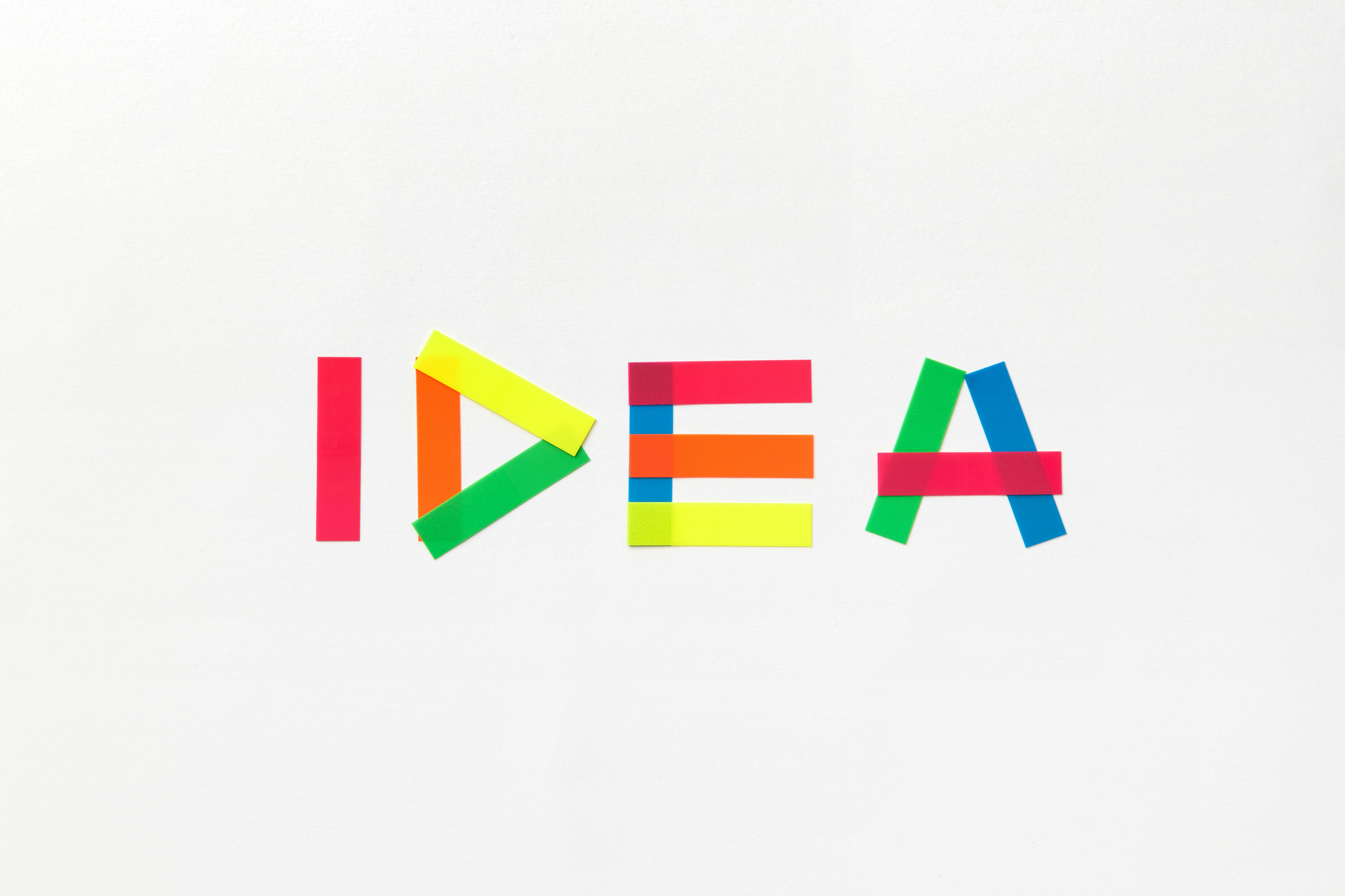Vibrant colored tape spells 'IDEA' on a clean white background, symbolizing creativity.