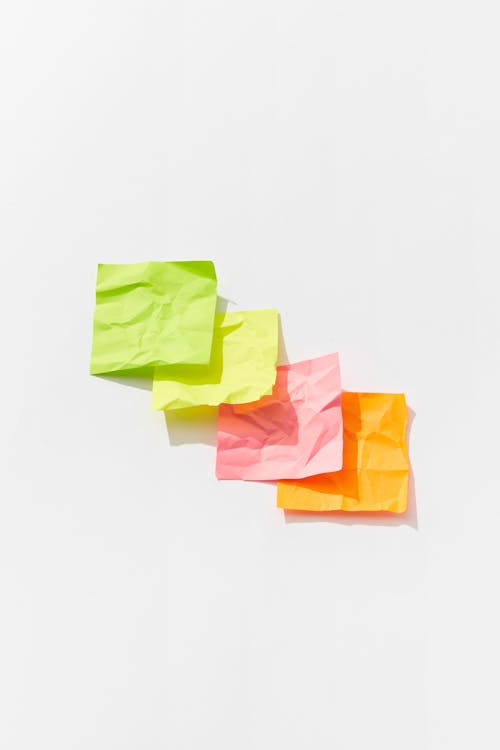 A Few Pieces of Crumpled Sticky Notes on a White Surface · Free Stock Photo