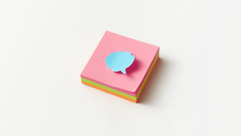 A stack of colorful sticky notes with a blue cloud-shaped note on top, perfect for creative office concepts.