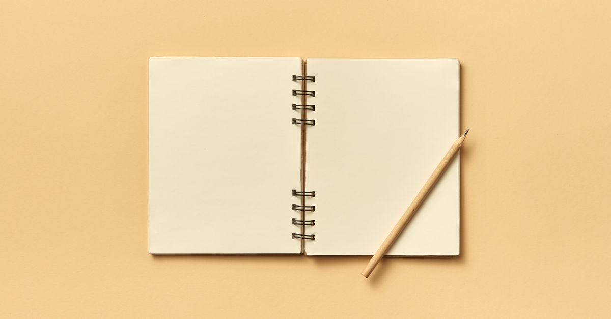An open spiral notebook with a pencil on a neutral beige background, perfect for creative projects and planning.
