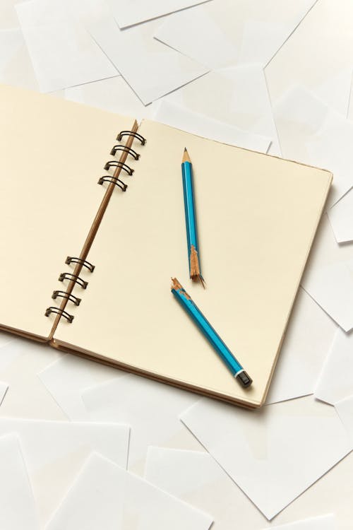 Free A Notebook with a Broken Pencil on Scattered White Papers Stock Photo
