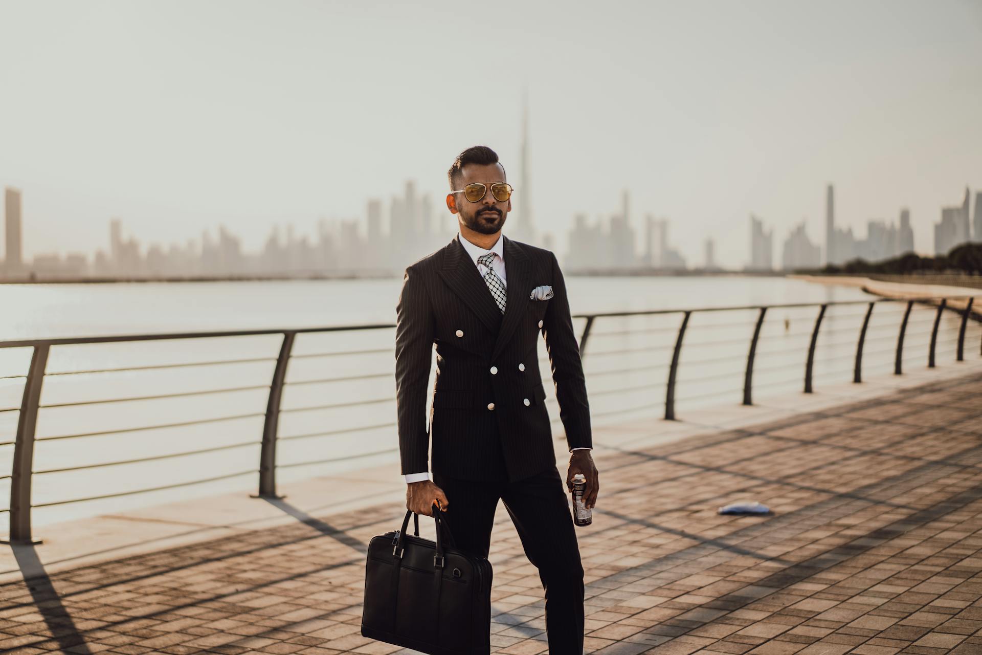 A Man in Black Suit Holding a Black Briefcase and a Canned Drink