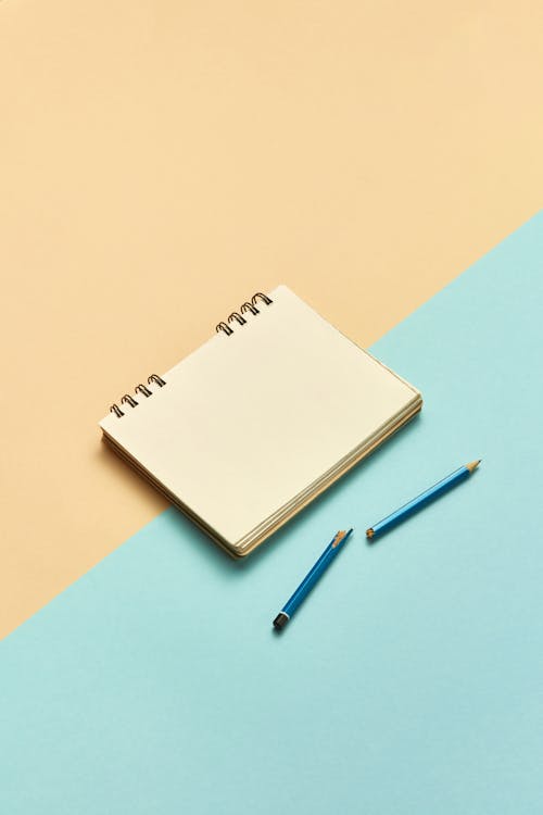 Free A Beige Notebook Beside a Broken Pencil Stock Photo