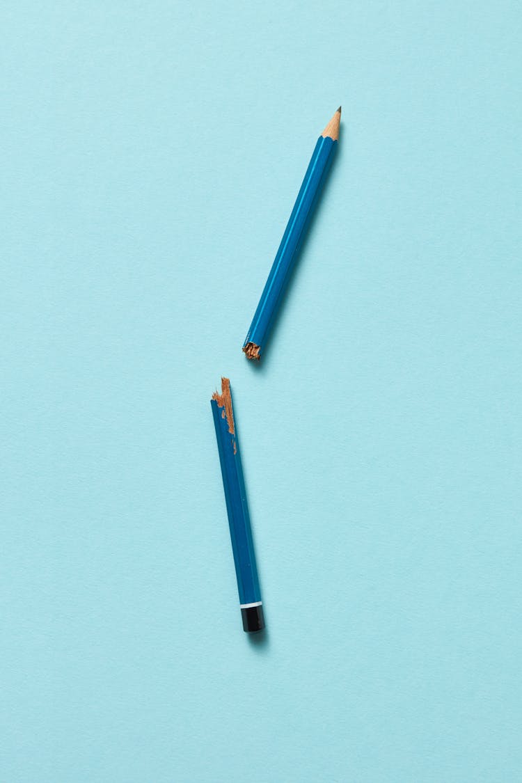 A Broken Wooden Pencil On A Blue Surface