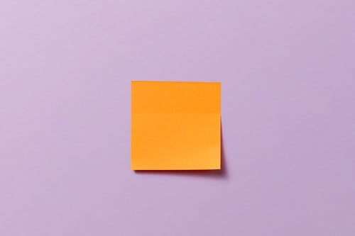 Free A Blank Sticky Note Stuck on a Lilac Surface Stock Photo
