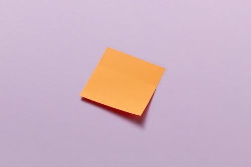 An Orange Sticky Note on a Purple Surface