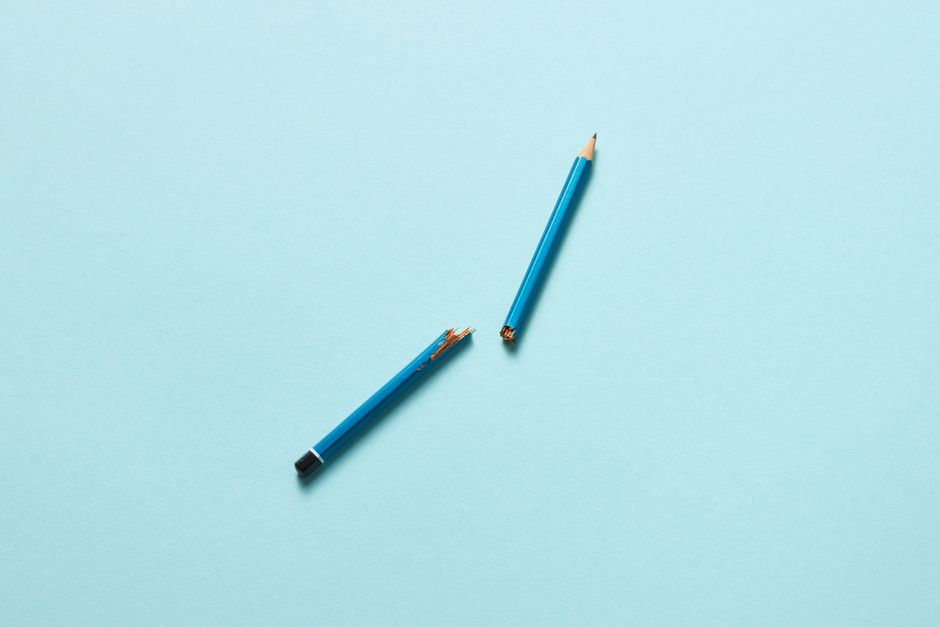 A conceptual image of a broken blue pencil on a light blue surface, symbolizing creativity and challenges.