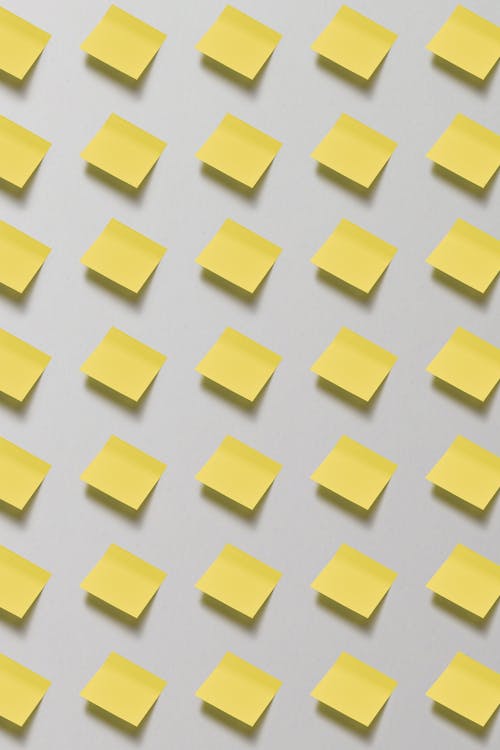 An Array of Blank Yellow Sticky  Notes Stuck on Wall