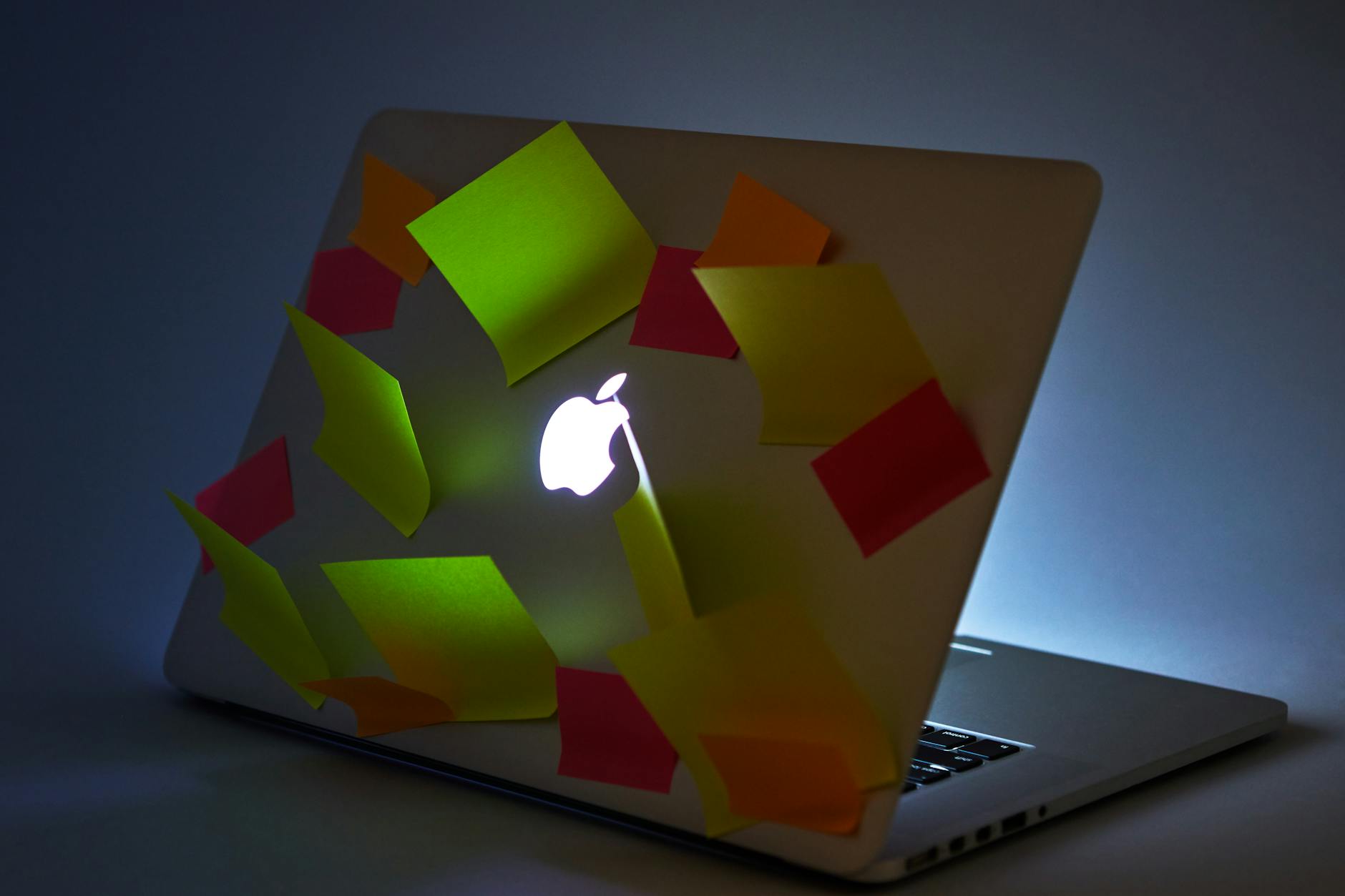 An Apple Laptop with Sticky Notes Stuck on Top Panel