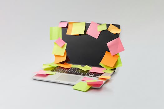 A laptop covered with colorful sticky notes for organization and reminders on a white surface.