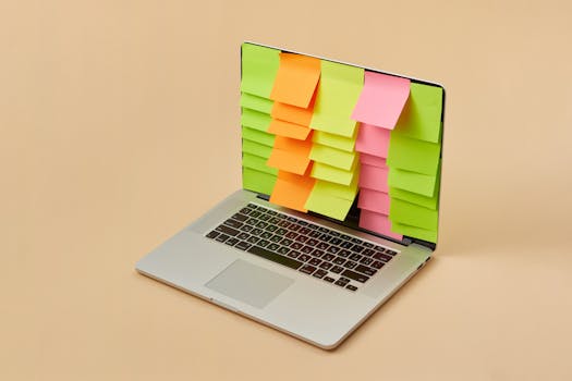 A sleek laptop with a screen covered in colorful sticky notes, depicting organization and task management.
