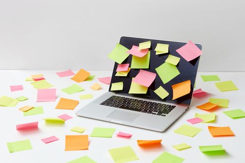 Free A laptop covered with colorful sticky notes on a white desk, symbolizing creative brainstorming and productivity. Stock Photo