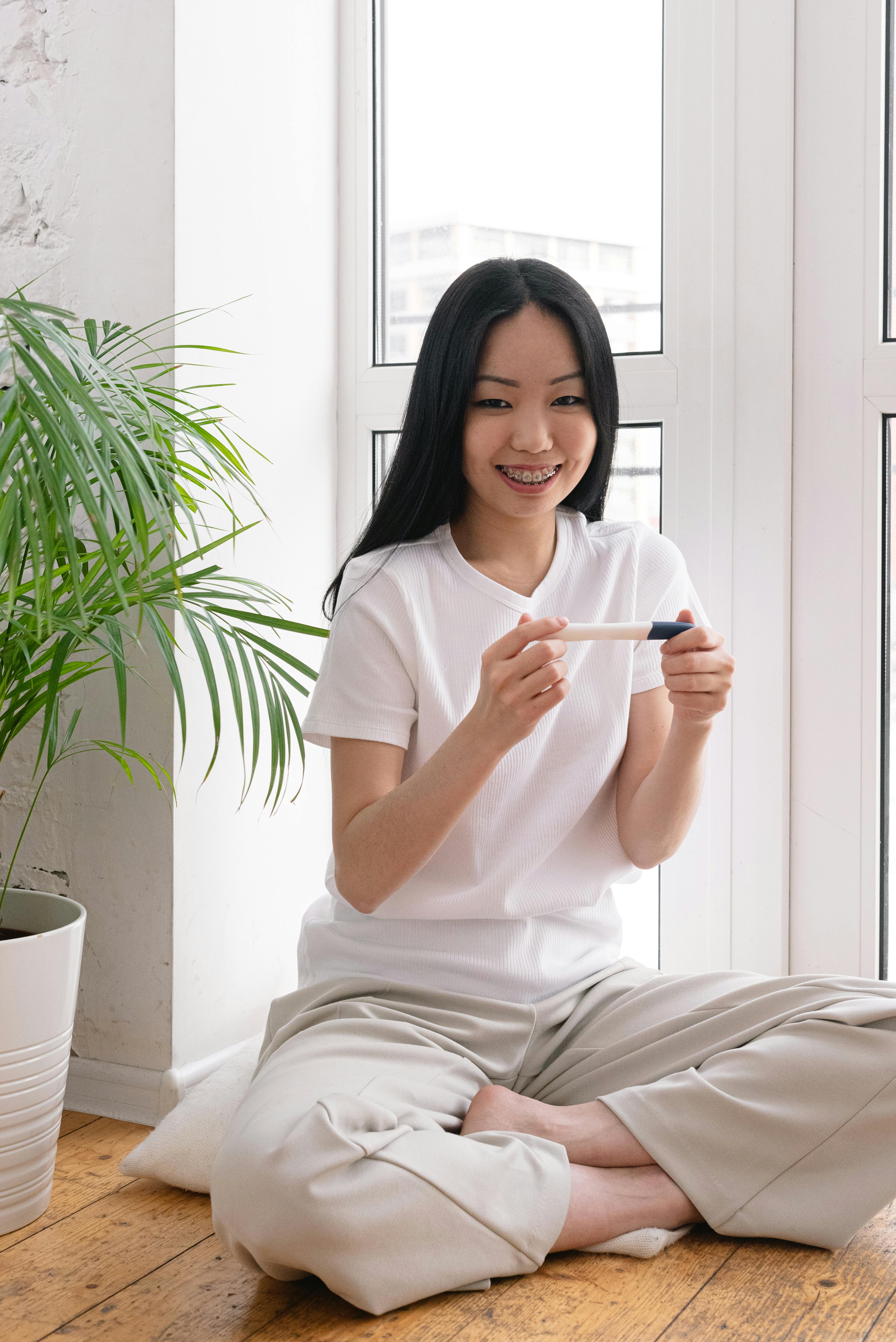 smiling asian woman with pregnancy test