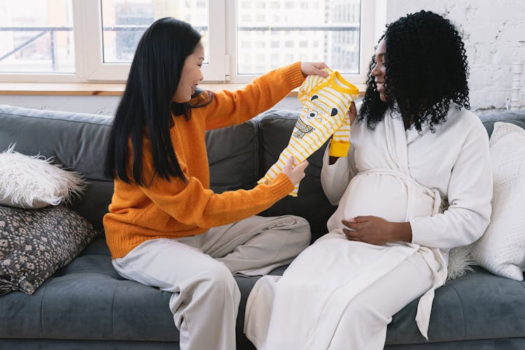 Cheerful Multiracial Lesbian Couple With Baby Clothes