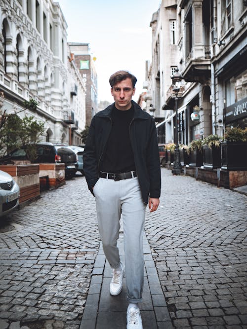 Young Fashionable Man Walking on a Cobblestone Street with His Hand in Pocket 
