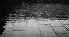 一张单色图像中，雨滴飞溅在潮湿的铺砌表面上