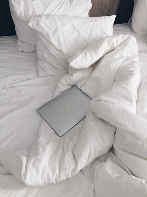 Laptop on unmade bed in morning